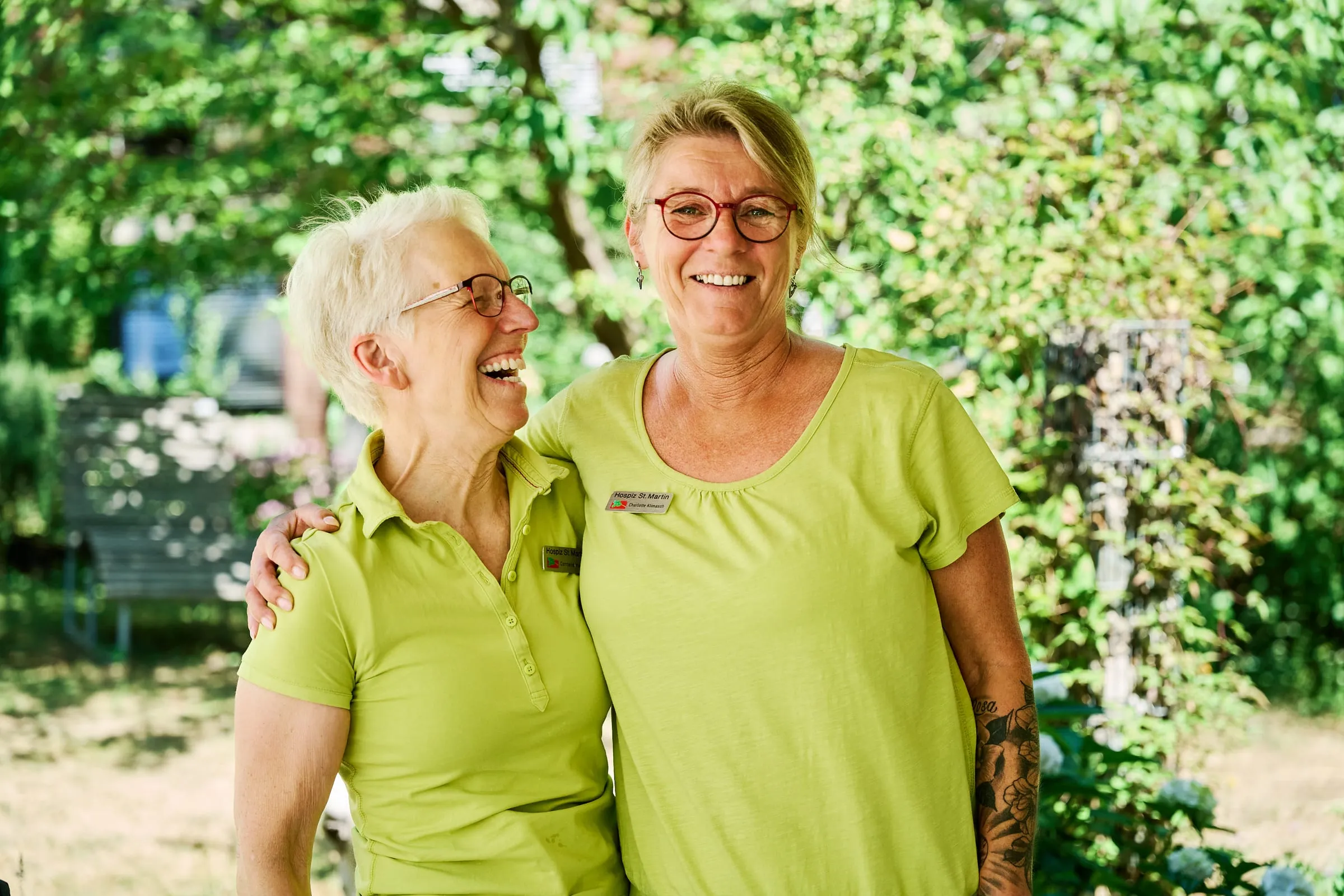 Zwei Mitarbeiterinnen des stationären Hospizes St. Martin lachen im Garten